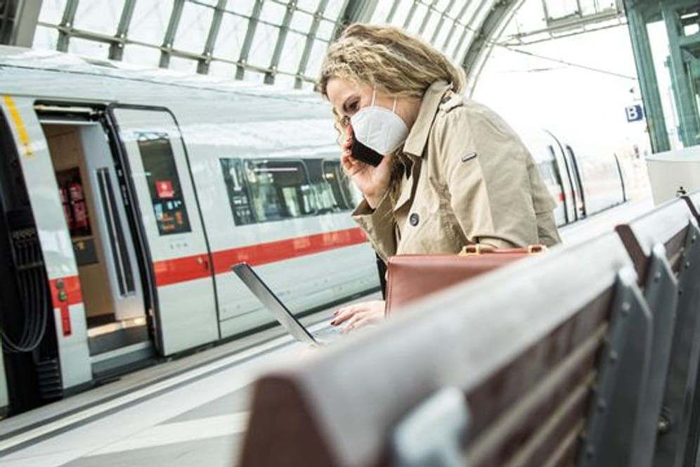 Frau arbeitet am Bahnhof (Symbolbild): Wenn mobiles Arbeiten vereinbart ist, geht das – im Gegensatz zur Telearbeit – von überall.