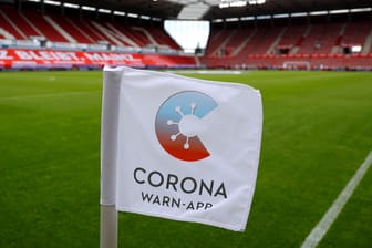 Ein Fähnchen mit dem Logo der Corona-Warn-App steckt im Rasen eines Fußball-Stadions: Version 1.7 der App wurde veröffentlicht.