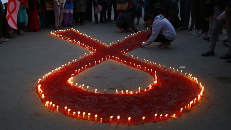 Aktivisten stellen auf einer Veranstaltung im Vorfeld des Welt-Aids-Tags Kerzen auf, die eine rote Schleife formen: Das weltweit anerkannte Symbol für die Solidarität mit HIV-Infizierten.