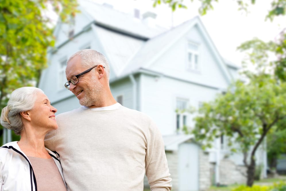 Ein älteres Ehepaar vor dem eigenen Haus (Symbolbild): Beim Teilverkauf bleiben Sie Nutzer Ihrer Immobilie.