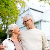Ein älteres Ehepaar vor dem eigenen Haus (Symbolbild): Beim Teilverkauf bleiben Sie Nutzer Ihrer Immobilie.