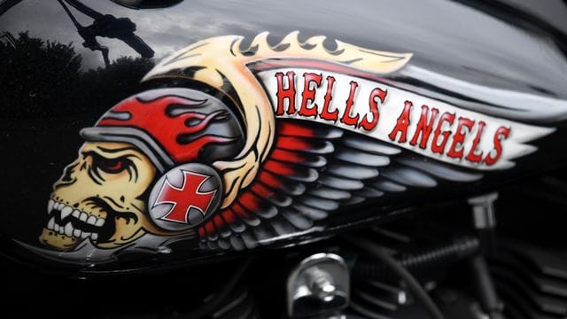 Das Hells Angels-Emblem, ein Totenkopf mit Helm und Flügeln, auf einem Tank eines abgestellten Motorrads. Das Hells Angels-Emblem, ein Totenkopf mit Helm und Flügeln, auf einem Tank eines abgestellten Motorrads.
