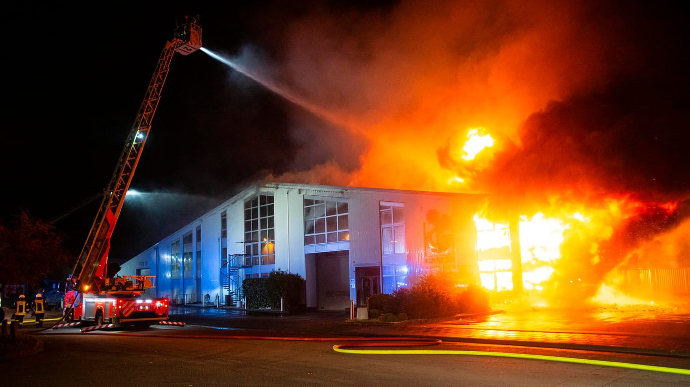 Feuerwehrleute löschen von einer Drehleiter aus den Brand einer Lagerhalle. Eine etwa 4.000 Quadratmeter große Lagerhalle im Kölner Stadtteil Lind ist fast vollständig ausgebrannt.