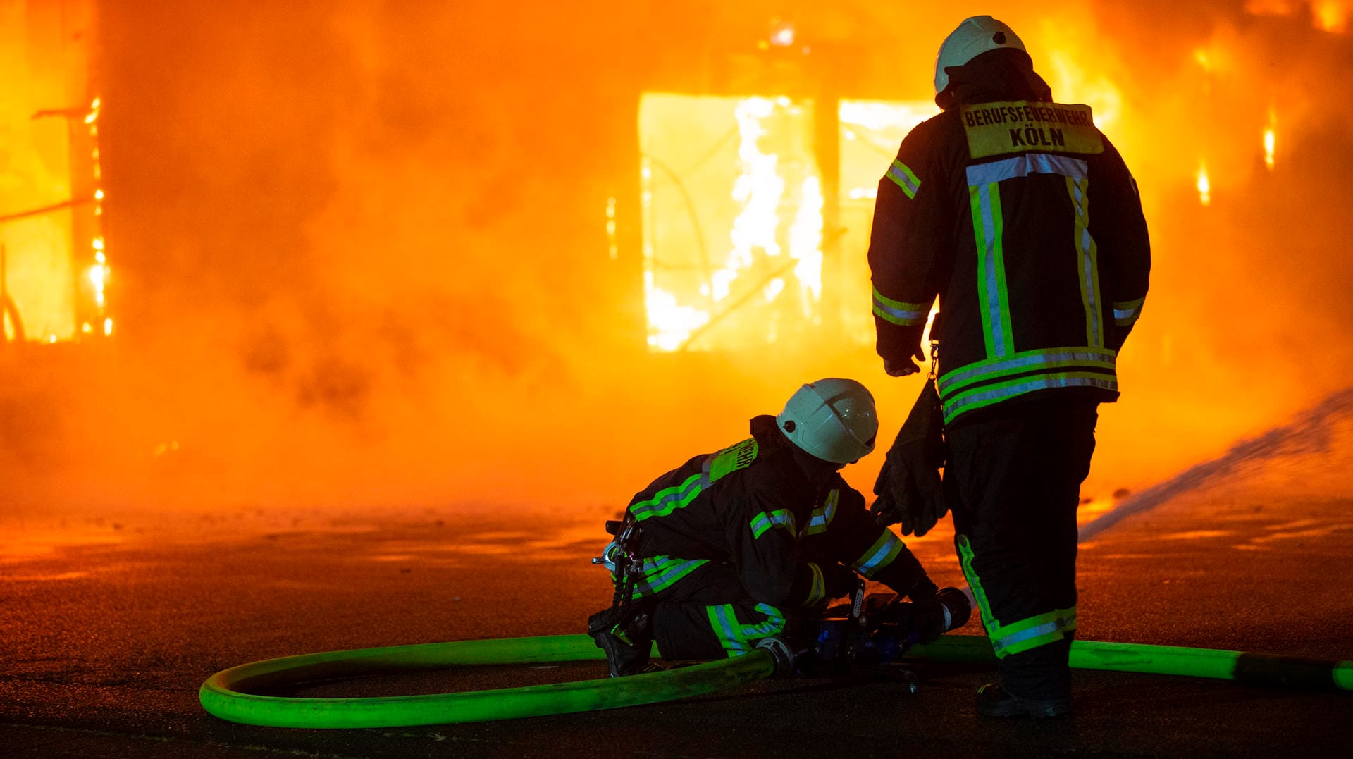 Feuerwehrleute stehen vor der brennenden Lagerhalle: Warum das Feuer ausgebrochen ist, war zunächst noch unklar.