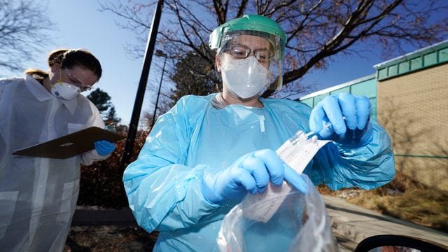 In der US-Stadt Denver führen zwei Gesundheitsmitarbeiterinnen bei einem Patienten einen Corona-Test durch.