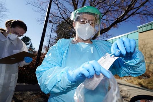 In der US-Stadt Denver führen zwei Gesundheitsmitarbeiterinnen bei einem Patienten einen Corona-Test durch.