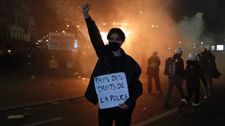 Demonstration in Paris: Ein Teilnehmer hält während eines Protestes gegen ein neues Sicherheitsgesetz ein Schild mit der Aufschrift "Land der Polizeirechte" in der Hand.