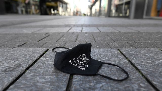 Ein verlorener Mundschutz liegt auf einer Einkaufsstraße. Ein verlorener Mundschutz liegt auf einer Einkaufsstraße.