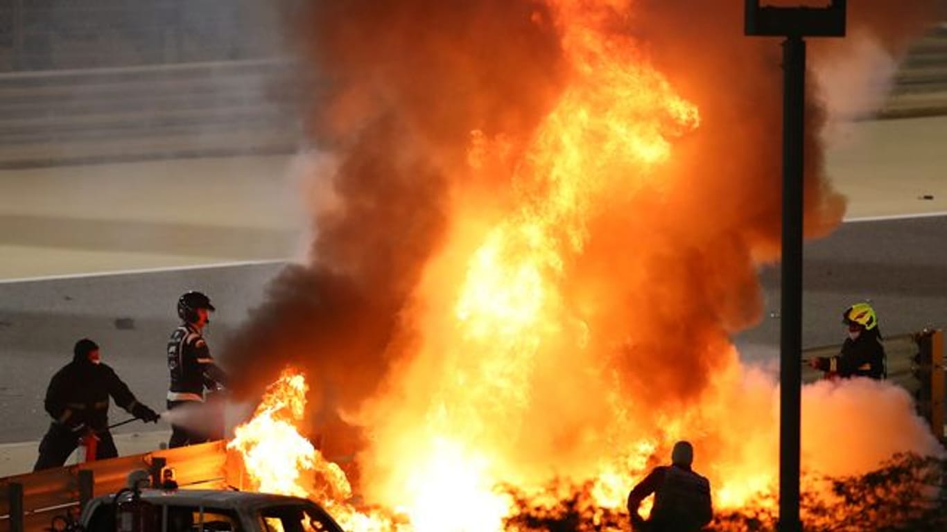 Mitarbeiter der Rennstrecke löschen das brennende Auto von Romain Grosjean.