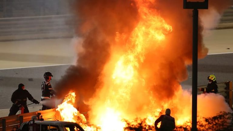 Mitarbeiter der Rennstrecke löschen das brennende Auto von Romain Grosjean.