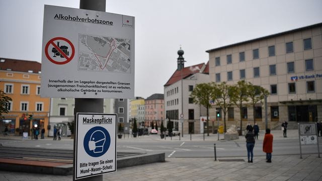 Schilder weisen am Ludwigsplatz auf die bestehende Alkoholverbotszone und die Maskenpflicht in Passau hin.