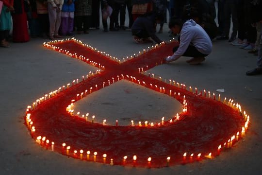 Eine rote Schleife aus Kerzen vor dem Welt-Aids-Tag