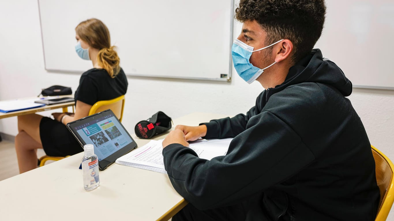Schüler sitzen mit Maske in einem Klassenzimmer (Symbolbild): Die Abiturprüfungen in Bayern beginnen in diesem Jahr später als angedacht.