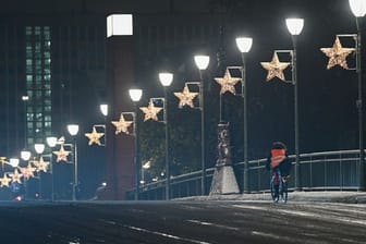 Ein Radfahrer ist nach einem Wintereinbruch in der Nacht auf der Alten Brücke in Frankfurt unterwegs.