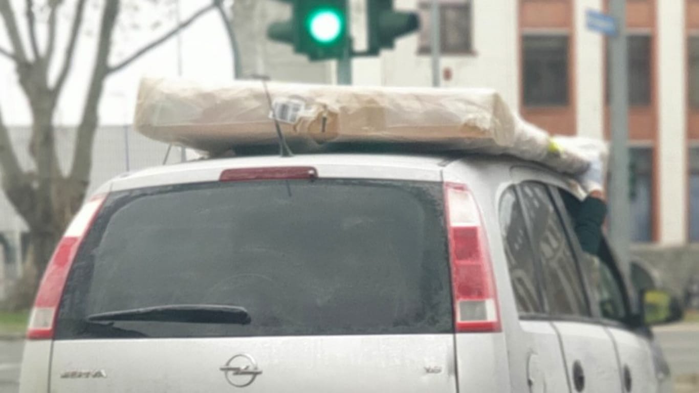 Ein Beifahrer hält eine Matratze auf einem Autodach fest: Diese kuriose Transportmethode rief in Hagen die Polizei auf den Plan.