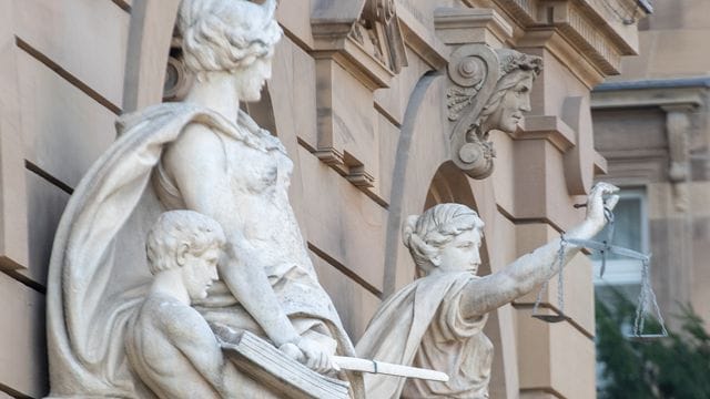 Vor einem Gerichtsgebäude steht u.a. eine Statue der Justitia Vor einem Gerichtsgebäude steht u.a. eine Statue der Justitia