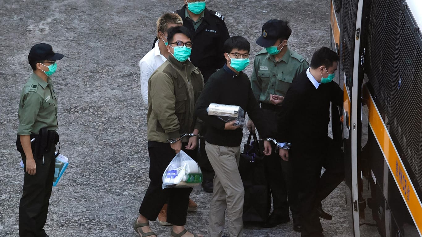 Ivan Lam (Mitte, l) und Joshua Wong (Mitte, r) steigen in einen Gefangenentransporter ein: Die Aktivisten wurden verurteilt.