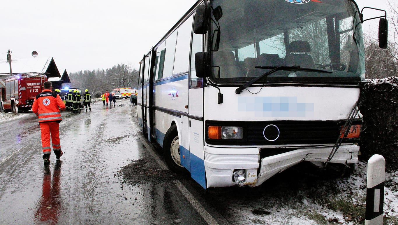 Ein beschädigter Schulbus steht an einer Unfallstelle: In den Unfall war eine 19-jährige Fahrerin mit ihrem Auto verwickelt, die schwer verletzt ins Krankenhaus kam.