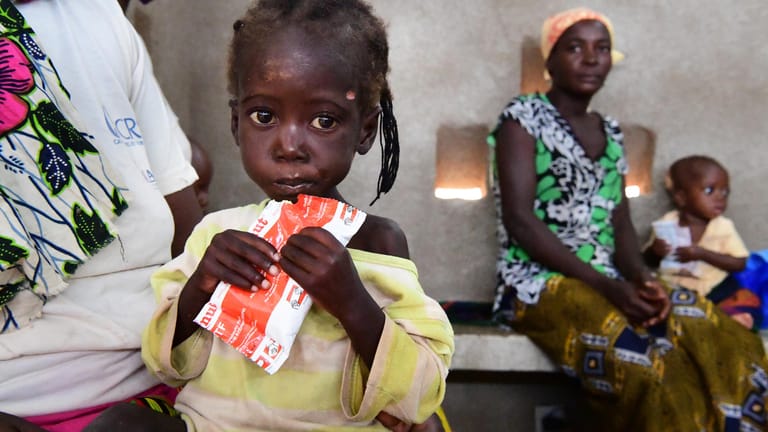 Ein kleines Mädchen isst Erdnussbutter-Paste in Burkina Faso (Westafrika): Durch die Corona-Pandemie wurden zusätzliche 130 Millionen Menschen in Hunger und extreme Armut zurückgeworfen.