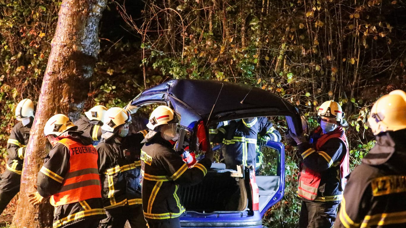 Feuerwehrleute schneiden ein Auto auf: Der Fahrer prallte in einer Kurve am frühen Morgen in einen Baum.