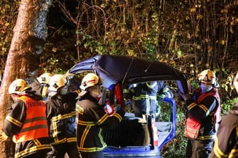 Feuerwehrleute schneiden ein Auto auf: Der Fahrer prallte in einer Kurve am frühen Morgen in einen Baum.