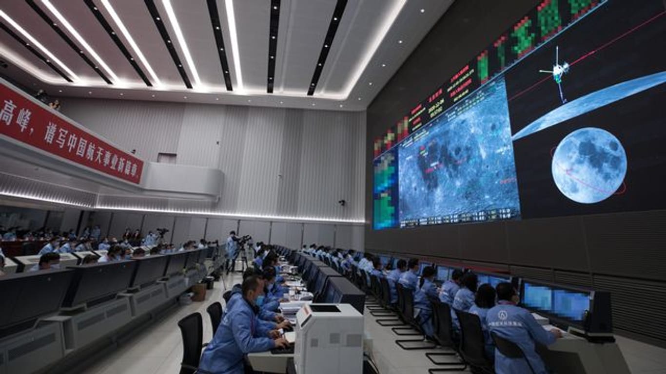 Technisches Personal überwacht den Transfer der auf dem Mond gesammelten Proben vom Aufstiegsmodul zum Rückkehrer der chinesischen Sonde "Chang'e 5" im Beijing Aerospace Control Center.