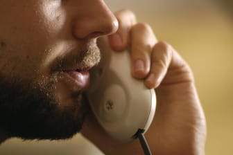 Ein Mann spricht in einen Telefonhörer: Die Bundesnetzagentur geht gegen betrügerische Geschäftsmodelle mit Callcentern vor.