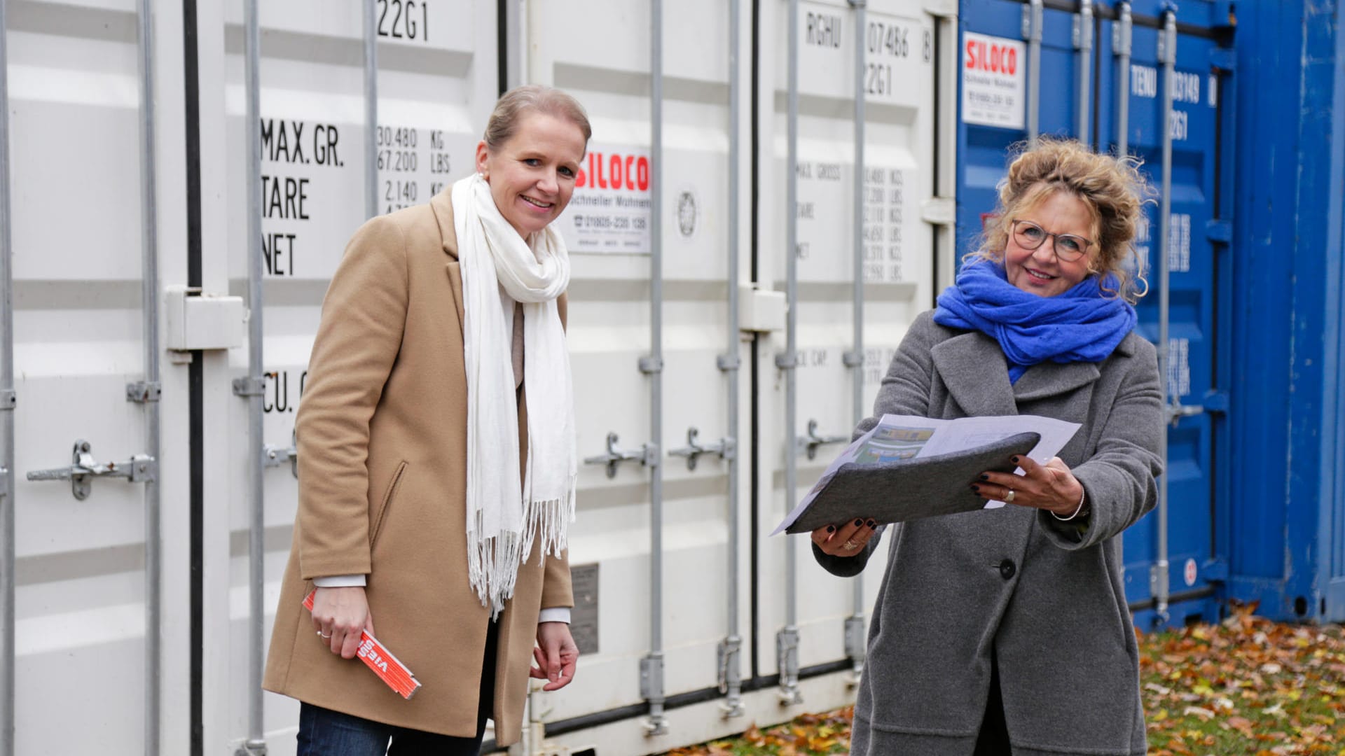 Karin Helmer und Maike Briege stehen vor den Containern für die Tiny Houses. Das Wohnprojekt ist auf Spenden angewiesen.