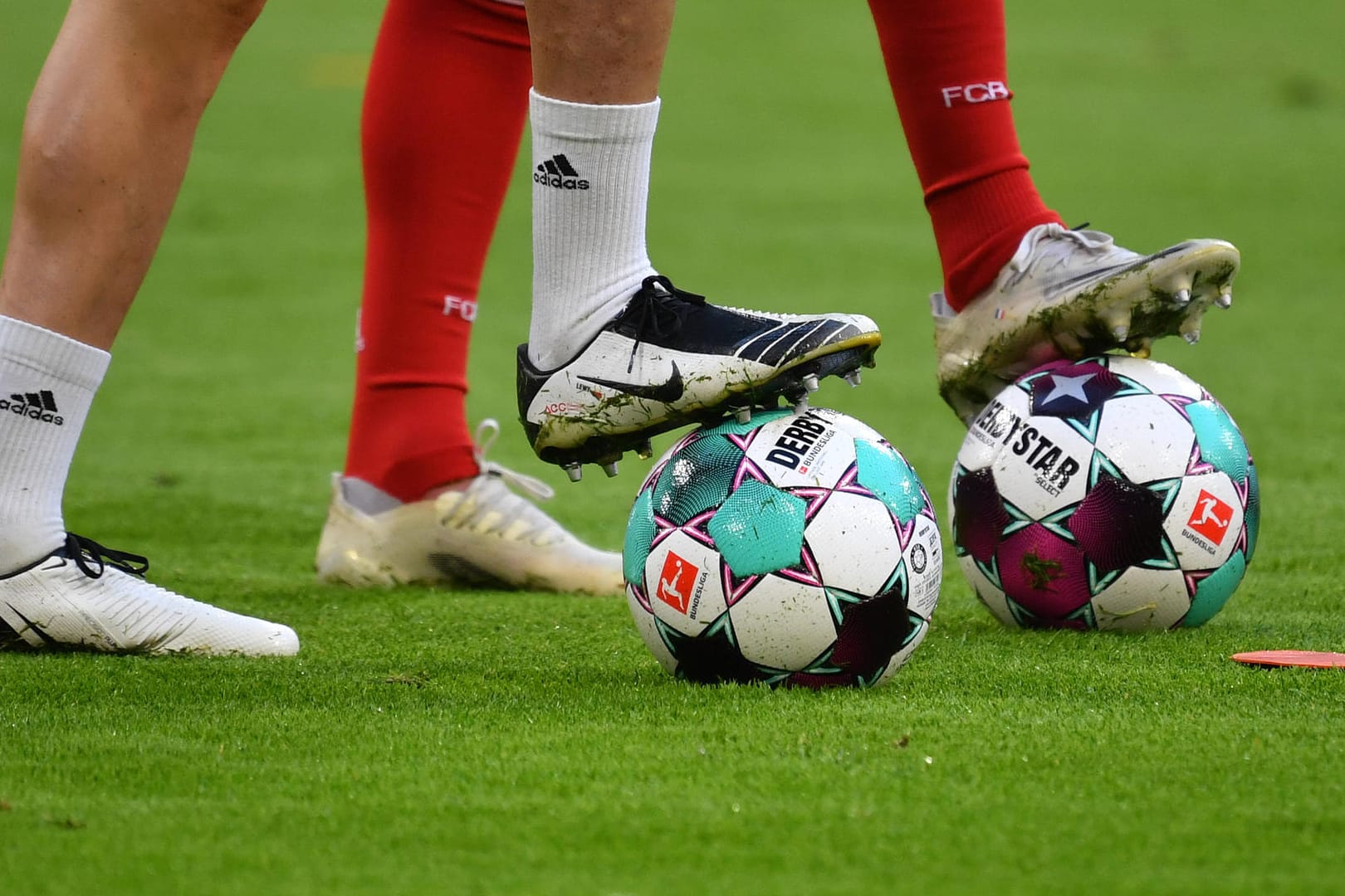 Zwei Spieler stellen einen Fuß auf Fußbälle (Symbolbild): Die nächste Bundesliga-Saison startet im August.