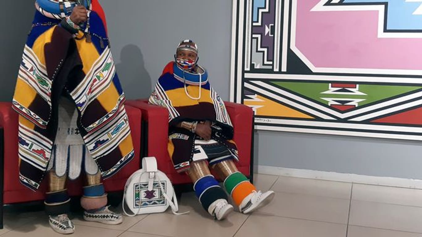 Traditionell gekleidet spricht Südafrikas Künstlerin Esther Mahlangu (l) neben einer Verwandten in einer Galerie.