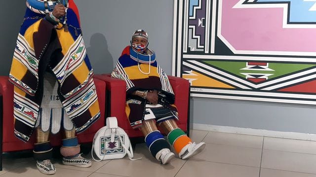 Traditionell gekleidet spricht Südafrikas Künstlerin Esther Mahlangu (l) neben einer Verwandten in einer Galerie. Traditionell gekleidet spricht Südafrikas Künstlerin Esther Mahlangu (l) neben einer Verwandten in einer Galerie.