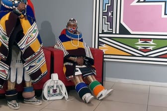 Traditionell gekleidet spricht Südafrikas Künstlerin Esther Mahlangu (l) neben einer Verwandten in einer Galerie.