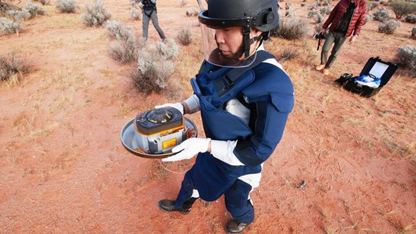 Ein Wissenschaftler hält in der Wüste des Woomera-Testgeländes für Luft- und Raumfahrt im Süden Australiens die Probenkapsel der japanischen Raumsonde "Hayabusa2".