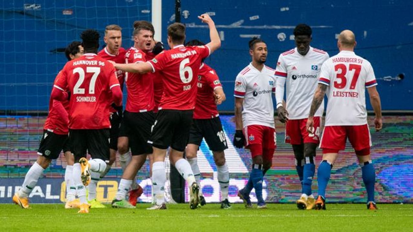 Hannovers Spieler feiern den Treffer zur 1:0-Führung, während die Hamburger (r) damit hadern.