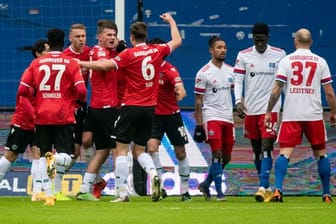 Hannovers Spieler feiern den Treffer zur 1:0-Führung, während die Hamburger (r) damit hadern.