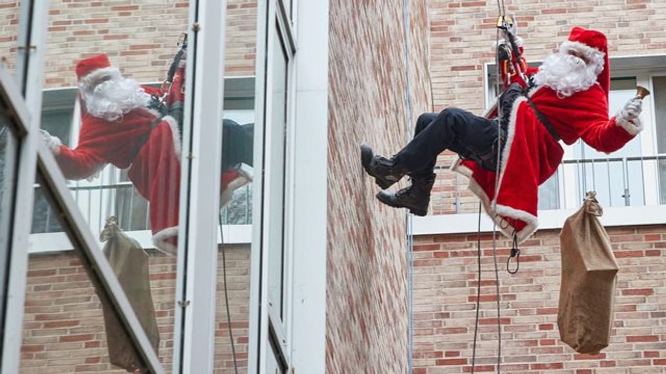 Ein als Nikolaus verkleideter Feuerwehr-Höhenretter seilt sich vom Dach der Kinderklinik ab: Die kleinen Patienten staunten am Sonntag nicht schlecht über den außergewöhnlichen Besuch.