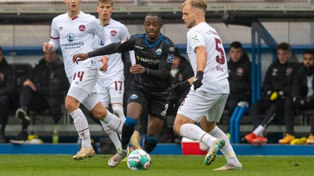 Paderborns Christopher Antwi-Adjei (M) und Nürnbergs Johannes Geis (r) im Zweikampf um den Ball.