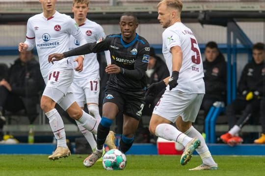 Paderborns Christopher Antwi-Adjei (M) und Nürnbergs Johannes Geis (r) im Zweikampf um den Ball.