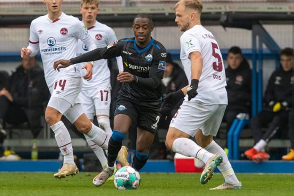 Paderborns Christopher Antwi-Adjei (M) und Nürnbergs Johannes Geis (r) im Zweikampf um den Ball.
