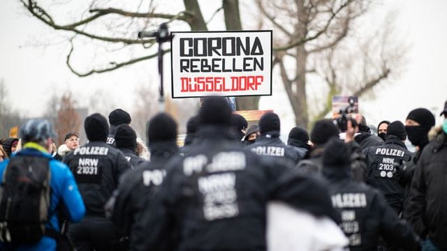 Teilnehmer einer Demonstration am Rheinufer mit Schild "Corona Rebellen Düsseldorf": Die Gegendemonstration war etwa genau so groß wie die der Querdenker. Teilnehmer einer Demonstration am Rheinufer mit Schild "Corona Rebellen Düsseldorf": Die Gegendemonstration war etwa genau so groß wie die der Querdenker.