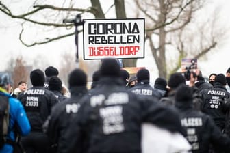 Teilnehmer einer Demonstration am Rheinufer mit Schild "Corona Rebellen Düsseldorf": Die Gegendemonstration war etwa genau so groß wie die der Querdenker.