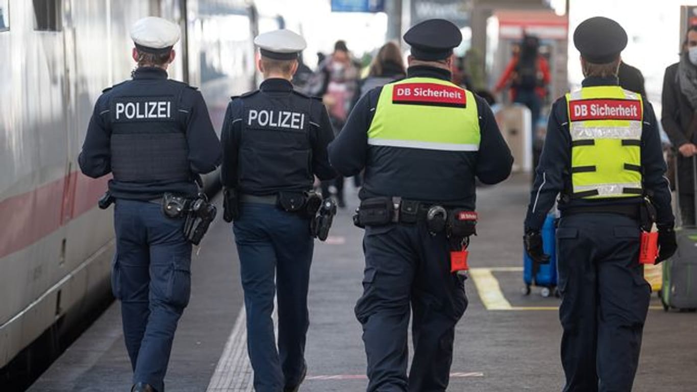 Polizeibeamte und Mitarbeiter der DB-Sicherheit kontrollieren am Stuttgarter Hauptbahnhof die Maskenpflicht.