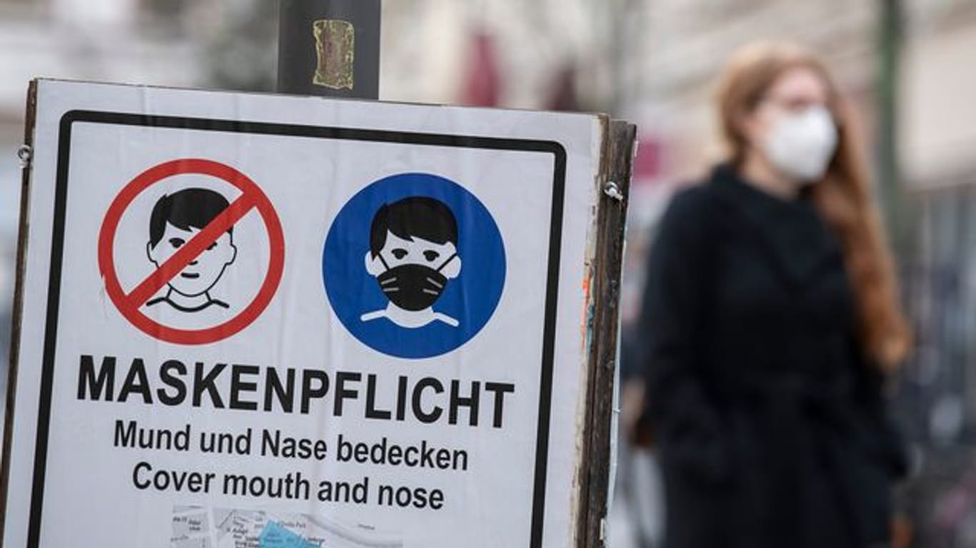 Plakate erinnern in einer fußgängerzone an die Einhaltung der Maskenpflicht.