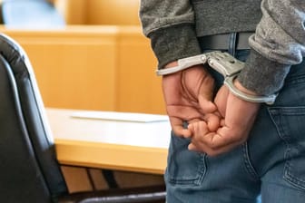Ein Angeklagter steht mit Handschellen in einem Gerichtssaal (Symbolbild): In der Türkei stand ein Arzt aus Wuppertal vor Gericht.