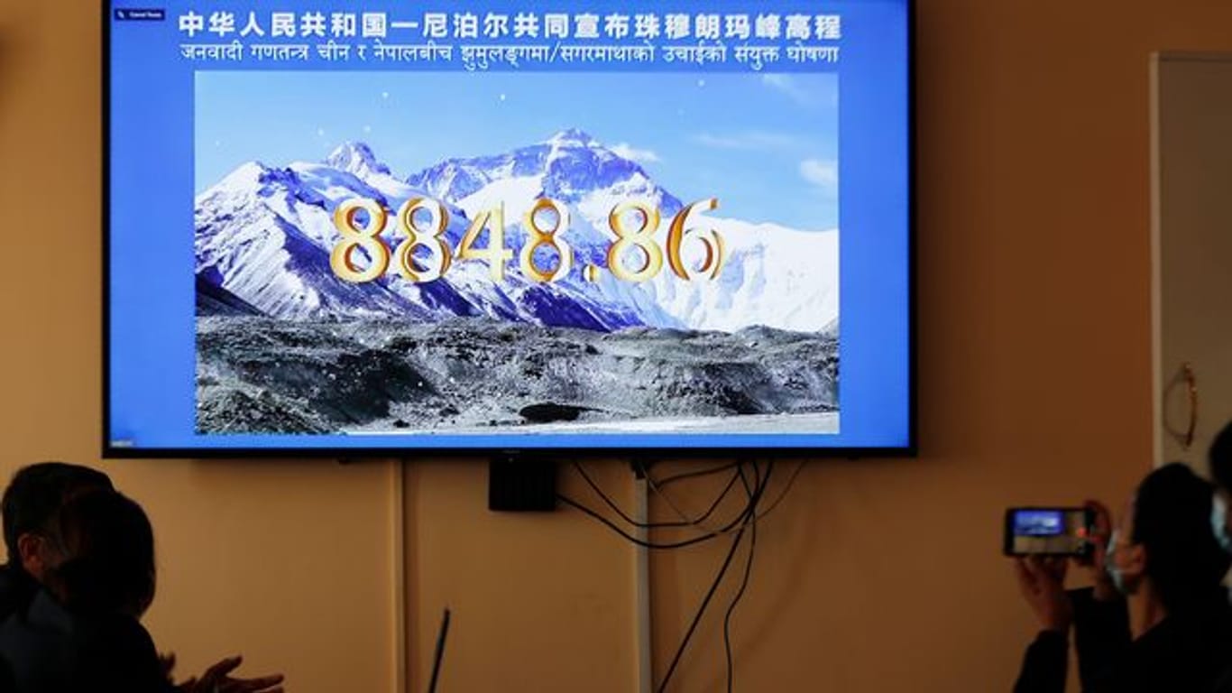Nepalesische Regierungsbeamte schauen eine gemeinsame Fernsehübertragung von Nepal und China, in der die offizielle Höhe des Mount Everests bekanntgegeben wird.