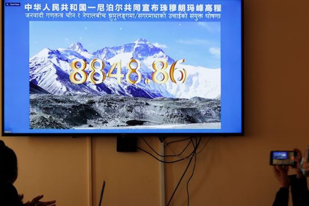 Nepalesische Regierungsbeamte schauen eine gemeinsame Fernsehübertragung von Nepal und China, in der die offizielle Höhe des Mount Everests bekanntgegeben wird.