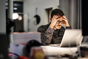 Ein Angestellter blickt erschöpft auf sein Laptop: Erst wenn alle Überstunden abgebaut sind, dürfen Arbeitnehmer Kurzarbeitergeld erhalten.