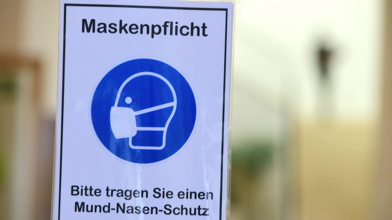 Ein Schild weist auf die Maskenpflicht in einem Gebäude hin (Symbolbild): In Hagen ist die Zahl der neuen Corona-Infektionen weiter hoch, was den OB "frustriert", wie er sagt.