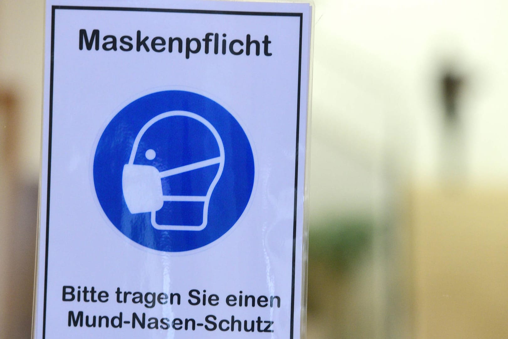 Ein Schild weist auf die Maskenpflicht in einem Gebäude hin (Symbolbild): In Hagen ist die Zahl der neuen Corona-Infektionen weiter hoch, was den OB "frustriert", wie er sagt.