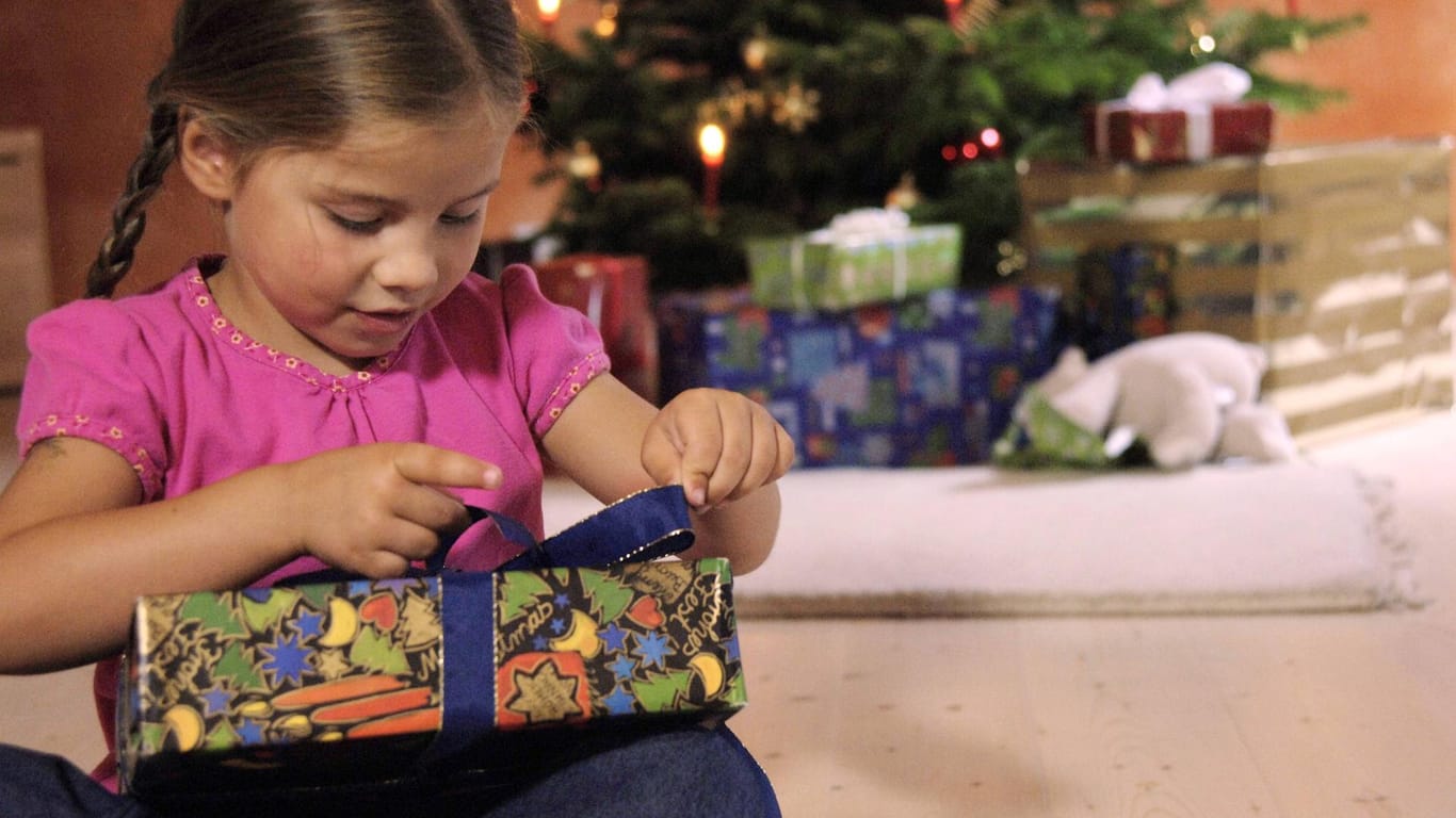 Ein Mädchen packt ein Weihnachtsgeschenk aus (Symbolbild): In Frankfurt organisiert das Kinderbüro eine Geschenkaktion für bedürftige Kinder.